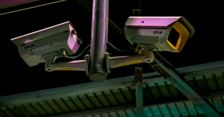 Pair of security cameras installed in an industrial setting with vibrant lighting.