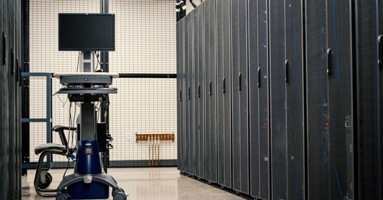 Contemporary computer on support between telecommunication racks and cabinets in modern data center