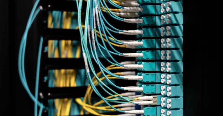Closeup of electronic device with colorful wires installed in rows in communications room on blurred background in dark studio inside